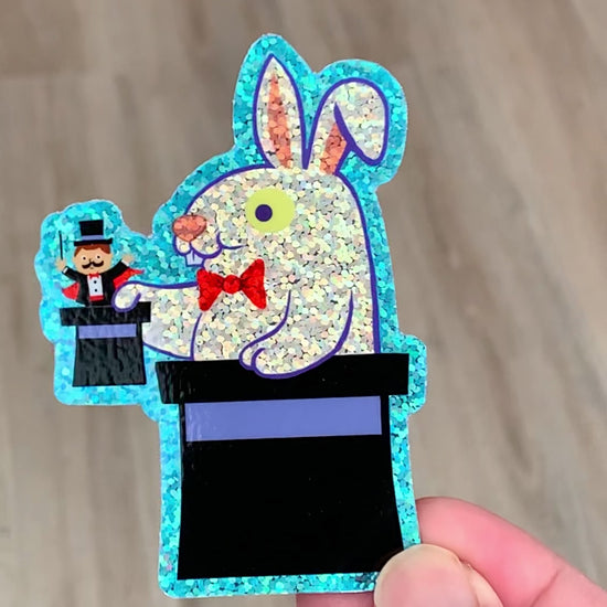 a rabbit pulling a tiny magician out of a top hat sticker with glitter effect